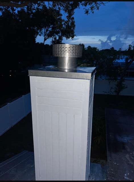 White-sided chimney chase with a metal top and round mesh cap