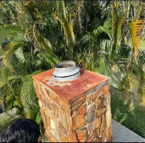 Stone-clad chimney with a rust-colored top plate and open round flue