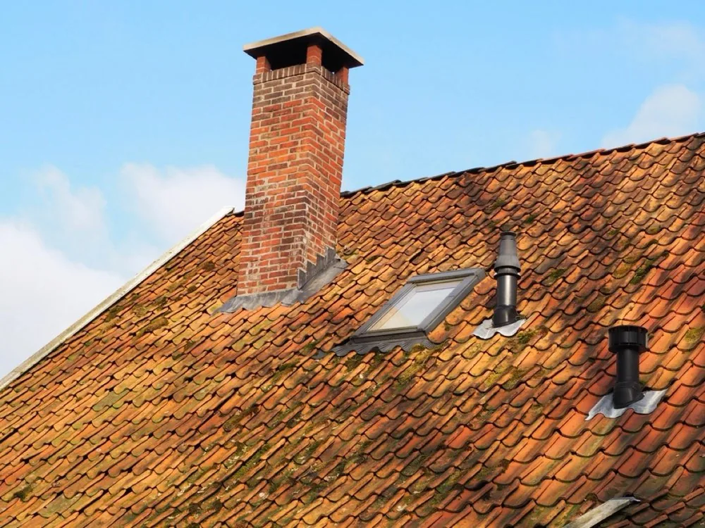 Brick chimney with concrete crown on a tiled roof